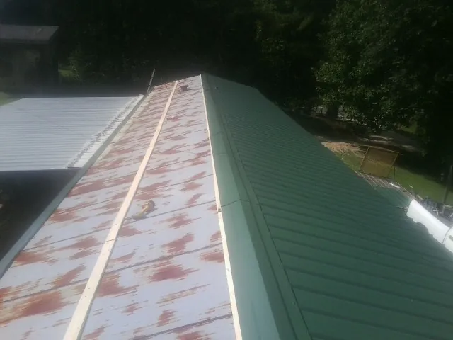 Old rusted panels beside newly installed green metal roofing — Wind Damage Roof Repair by Roofing Brothers in Dell