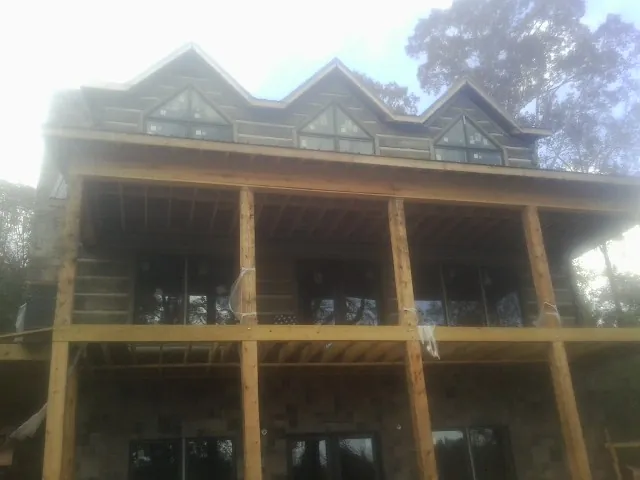 Dormers and porch framing on a large log home under construction — Roof Coating work by our crew in Dell