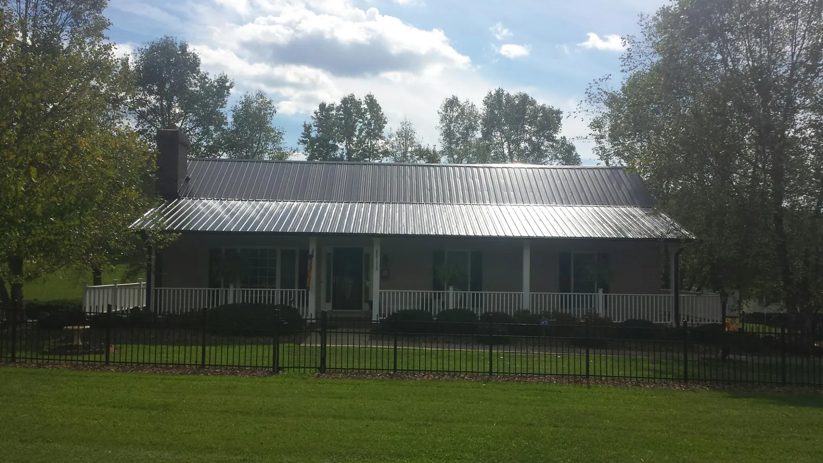 Gray metal roof on a brick ranch with a full width front porch — Gutter Guard Installation work by our crew in Dell