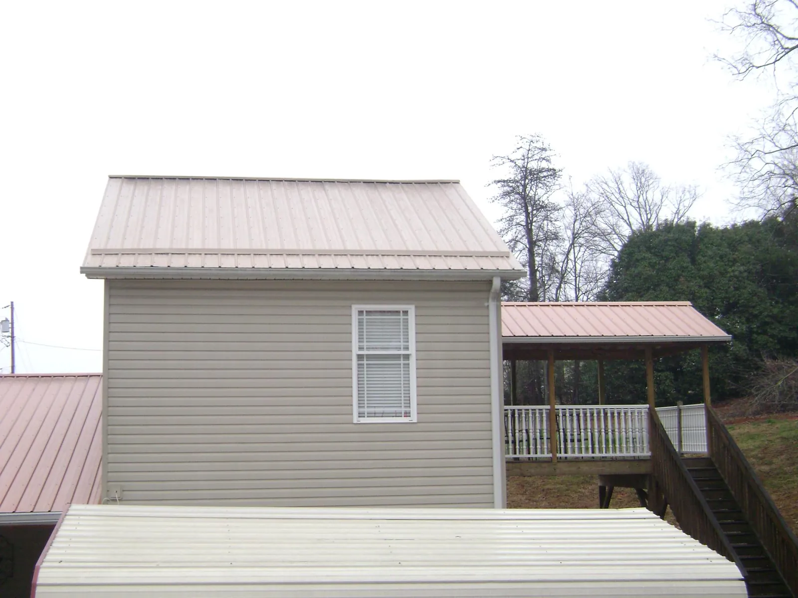 Tan metal roofs on a two story addition and attached porch, from a Roof Replacement job in Dell